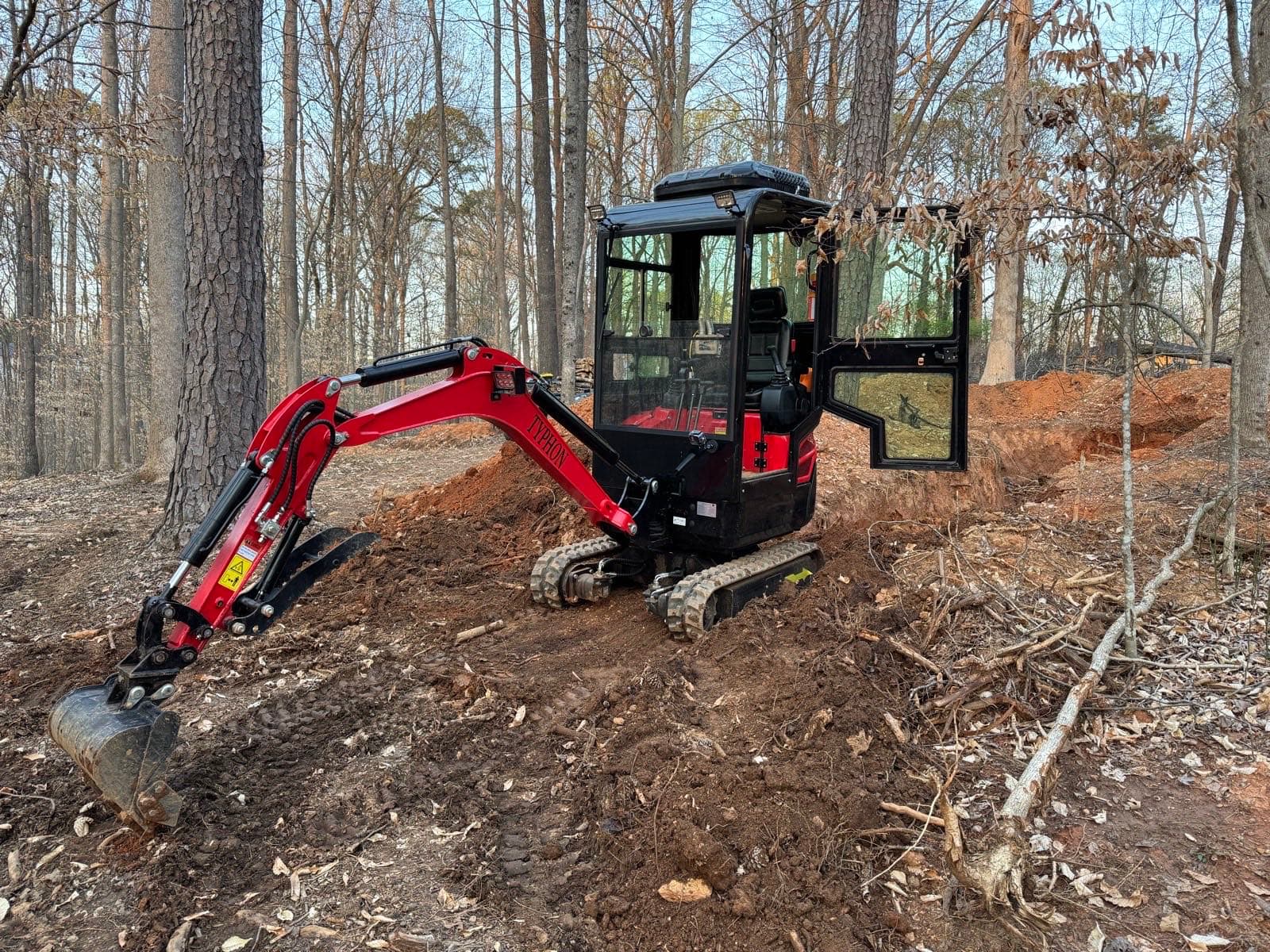 Mini excavator clearing a wooded residential lot